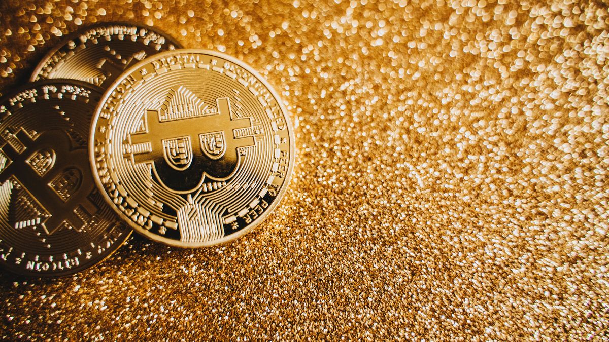 Gold-coloured Bitcoin coins on a bed of sparkling gold